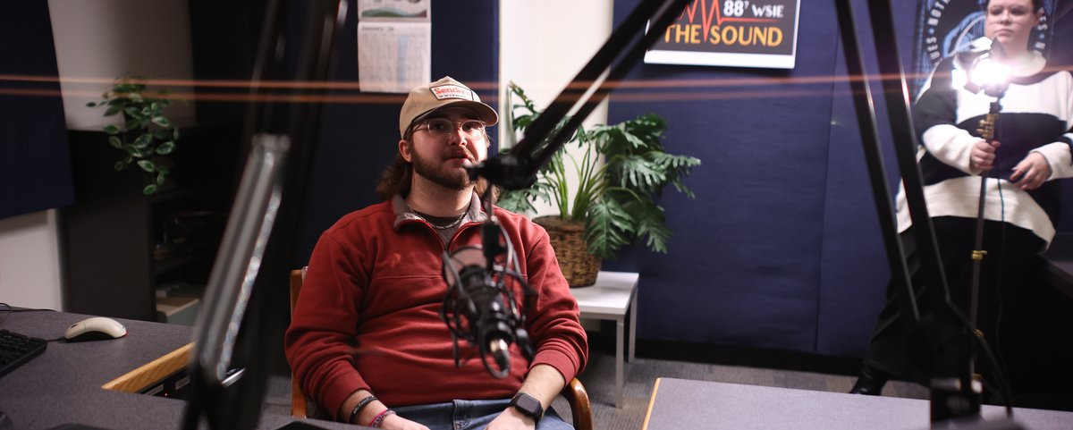 Student at the WSIE radio microphone in the audio production lab