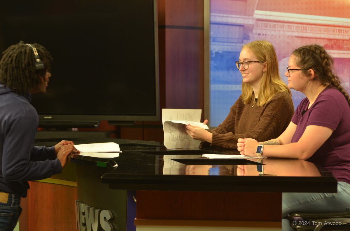 Journalism students reviewing scripts at the broadcast news desk