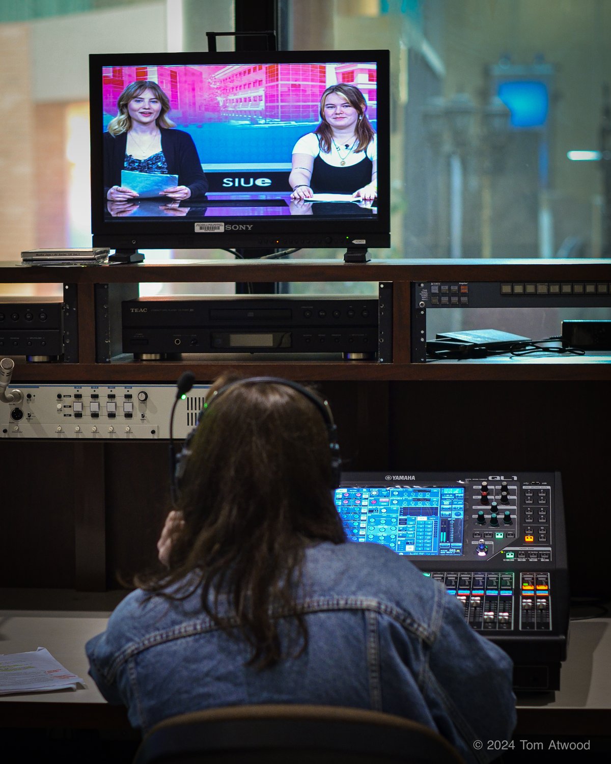 Student operating the production control board with talent visible on monitors
