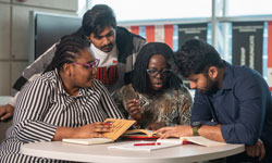Four SIUE students working at a table during a class project.