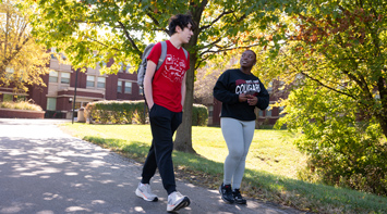 Two Students walking near a residence hall.