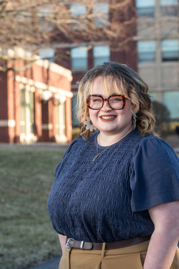 Portrait of Anjelikka Hopkins outside a residence hall beside a tree in early spring
