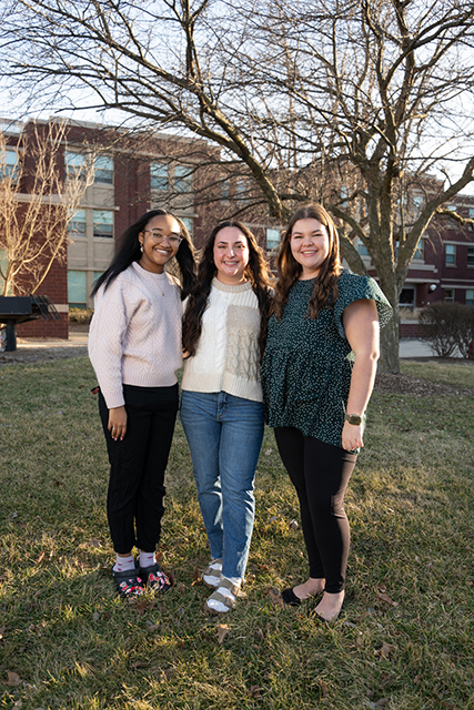 Woodland Hall Advisors Kiya Rainey, Sophie Parson, and Brianna Weaver standing outside Woodland Hall