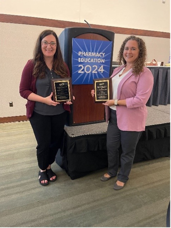 Kate Newman and Tessa Keys stand and hold their awards