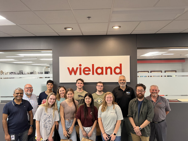 group of students and their professor standing in front of company sign