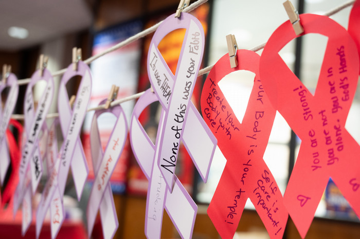 closeup shot of red and pink paper ribbons with positive messages written on them in sharpies