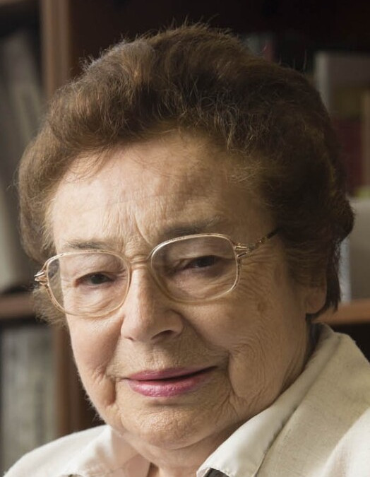 Portrait of Eva Dreikurs Ferguson, PhD, with short hair and glasses, seated indoors and looking toward the camera with a gentle expression.