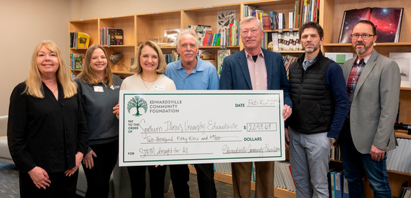 Seven people holding big check