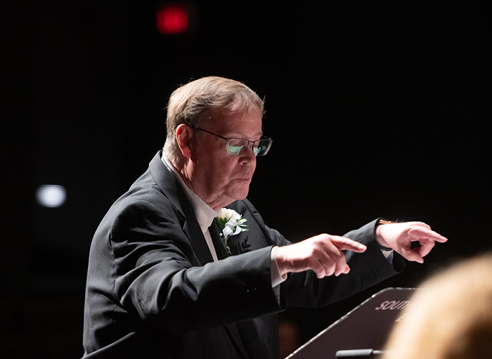 Professor Emeritus Brett Stamps conducting the SIUE Concert Jazz Band, his hands stretched in front as if to signal a pause