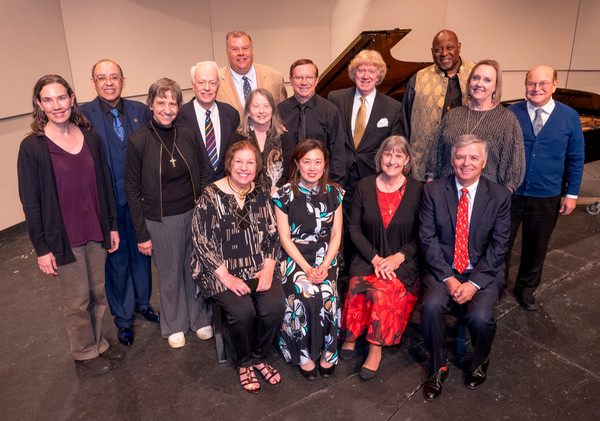High angle shot of group of pianists posing in front of piano