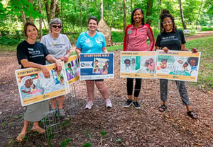 picture of SIUE staff around yard signs spaced out in the SIUE gardens showing a section of a story book