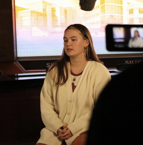 Kaylee sits with overhead microphone to record her podcast 