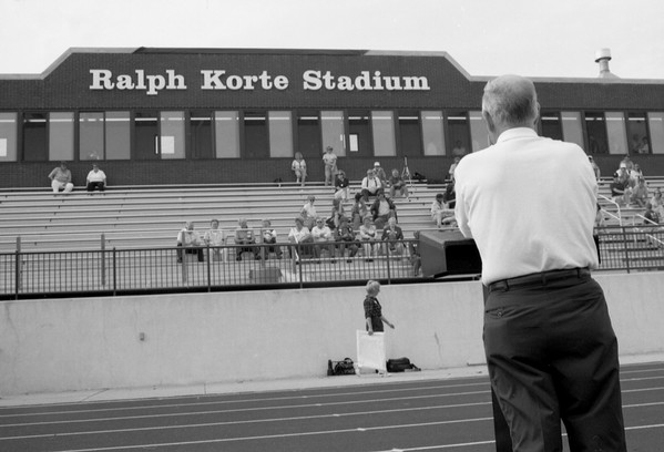 A landscape photo of Korte stadium, in black and white with Ralph Korte admiring the stands with his back to the camera.