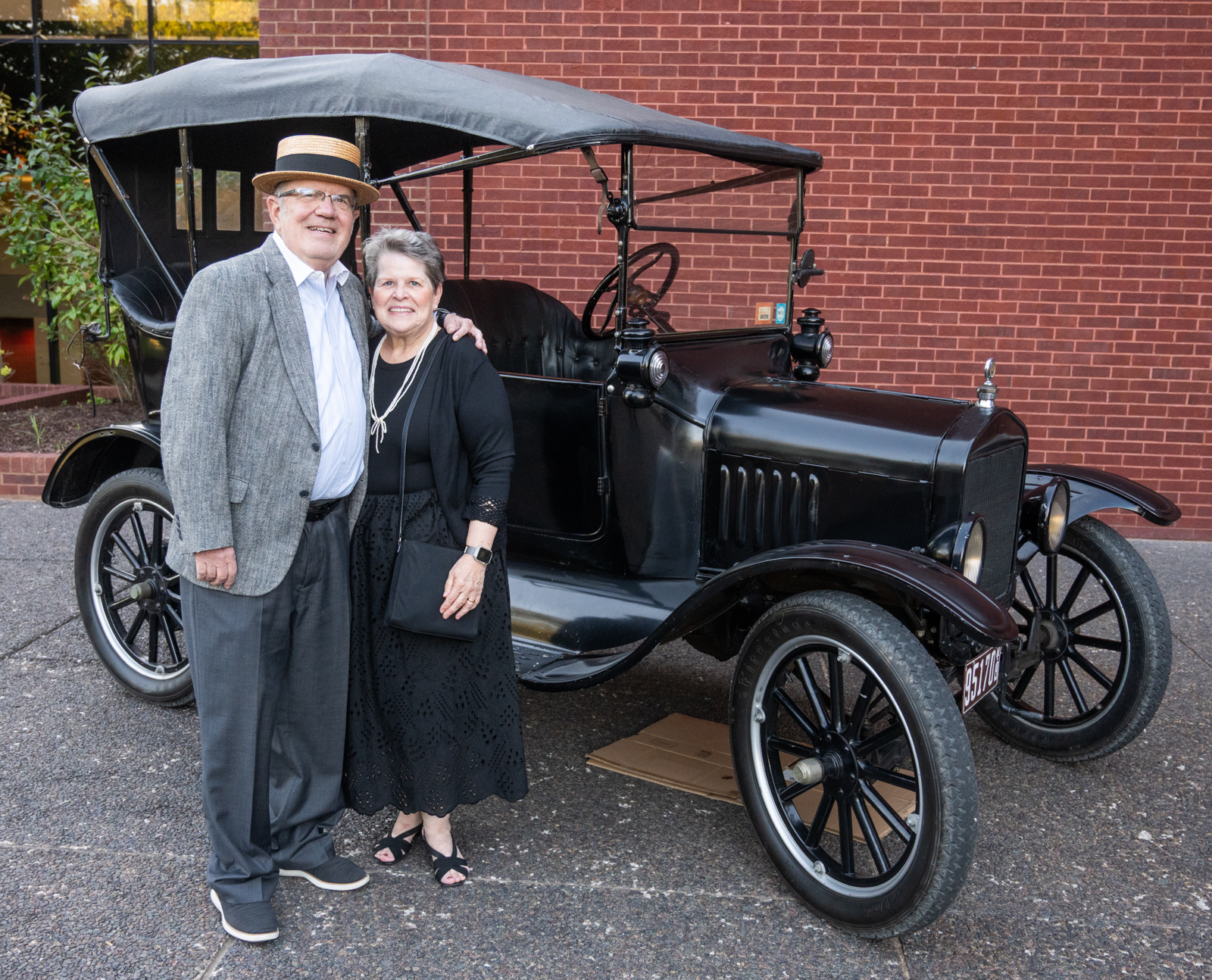 A Meridian Society member and her spouse, a gentleman dressed with a straw boater hat, in front of an original Ford Model T parked in front of Dunham Hall