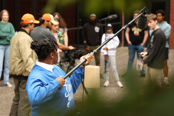 Students holding production equipment filming a scene