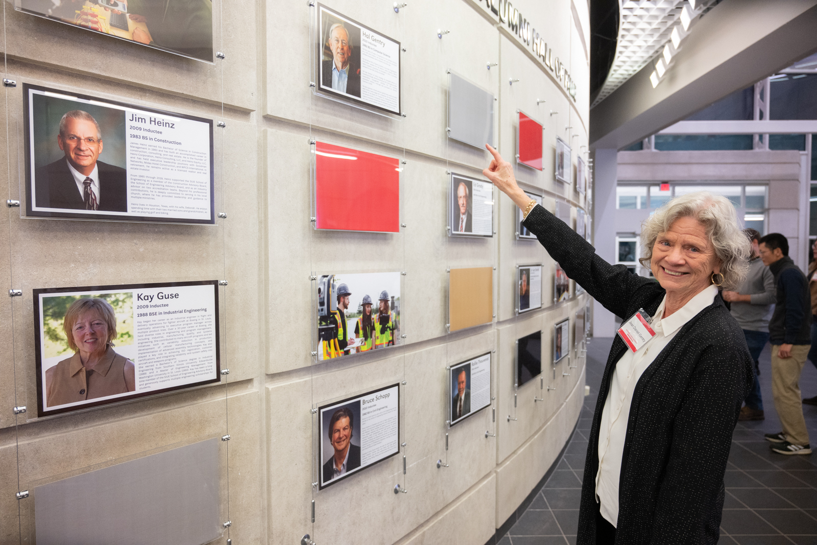 Photo of Jean Daniel-Gentry Pointing to her Partner's name and photo on the Wall of fame in the Engineering Building