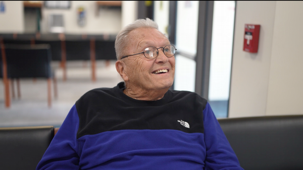 Veteran sits in chair and looks up and smiles