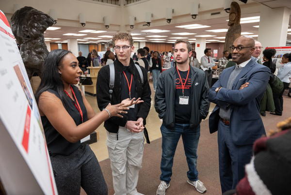 Scholar presenting poster presentation to classmates and Dr Minor