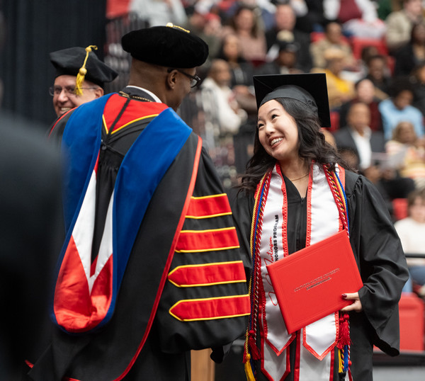 Megan You crosses stage and laughs with Chancellor Minor