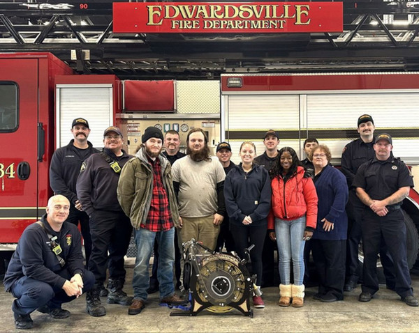 A group of students pose for a photo inside the Edwardsville Fire Department in front of a fire engine.