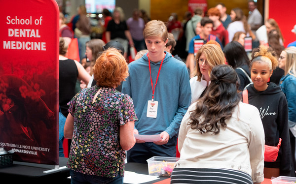 Crowd of students photographed from behind school of dental medicine info booth