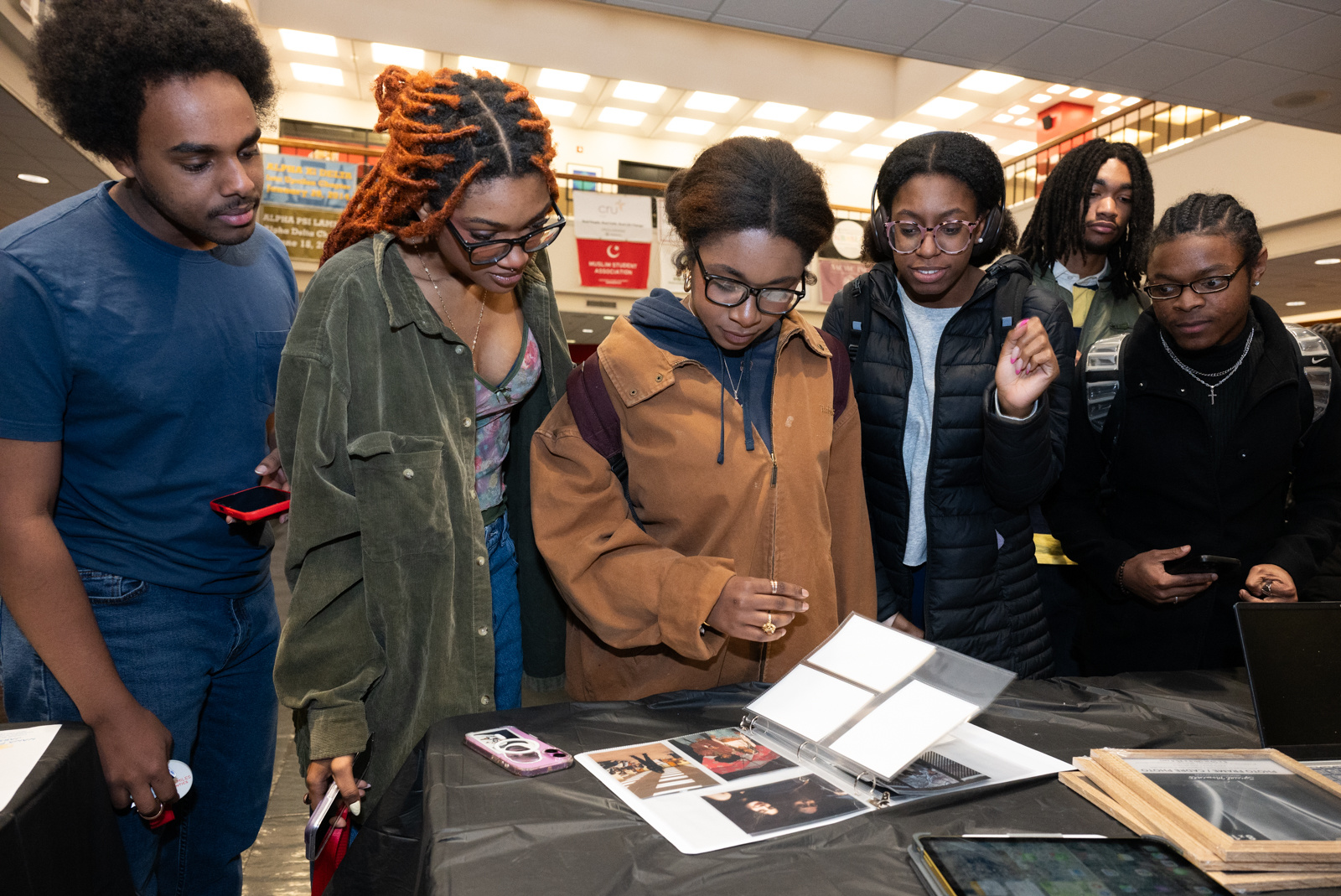 Students gather around a table to read displayed materials.