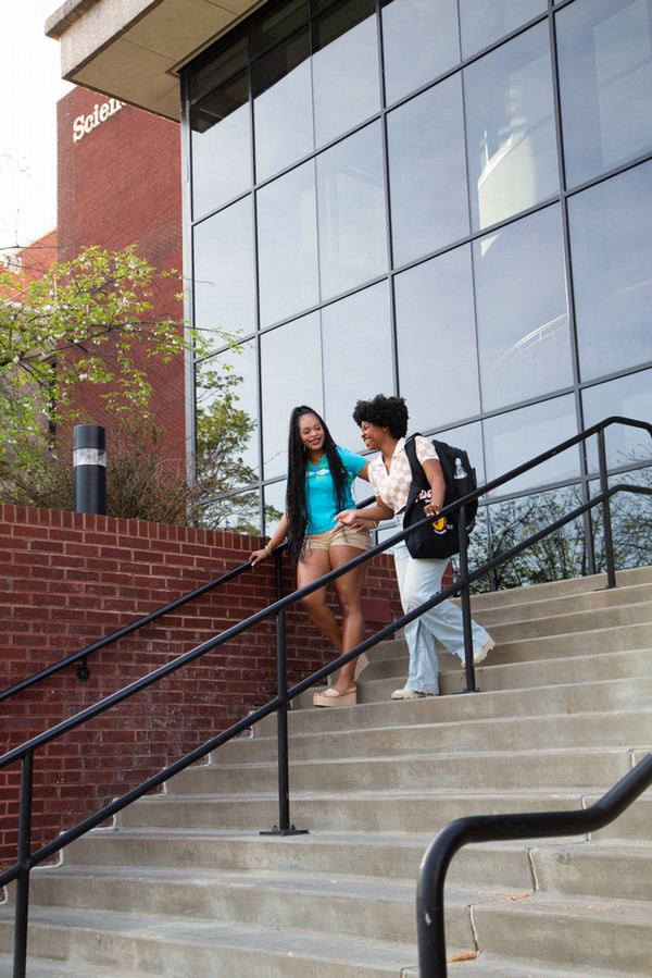 Two girls walking down the steps Science East bldg