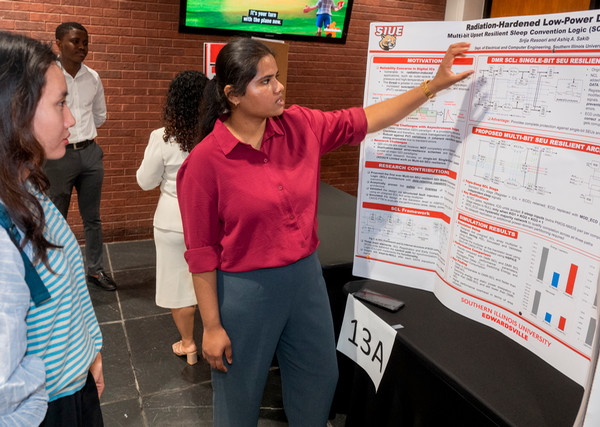 Student shows her poster project to person listening