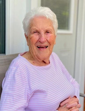 Portrait of a smiling Dixie Engleman sitting outside wearing a lilac striped blouse