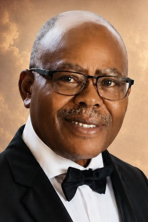 Formal head-and-shoulders portrait of an older Eneyo wearing glasses, a black tuxedo and black bow tie.
