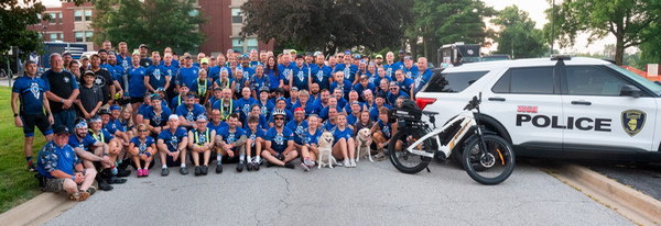 Group photo of dozens of Illinois police officers dressed in bikewear sitting and standing by SIUE PD vehicle