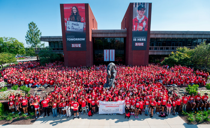 More than 2000 students and three service dogs pose with their banner in a high angle photograph in front of Morris University Center