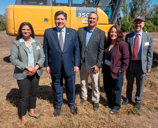 SIUE administrators and the Governor at Hollywood River Studios groundbreaking ceremony standing in dirt with a bulldozer behind them