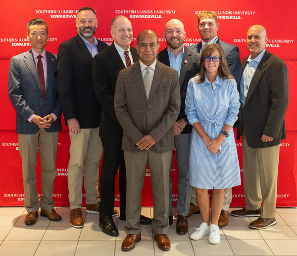 Group Photo of NCERC Executive Director Dr Dan Mahony Deans Rep Katie Stuart and Agriculture Industry posing for photo in front of SIUE background