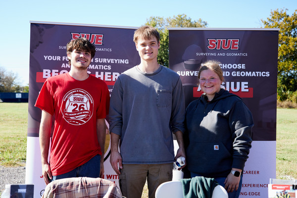Three engineering students stand in front of SIUE banner smiling to camera