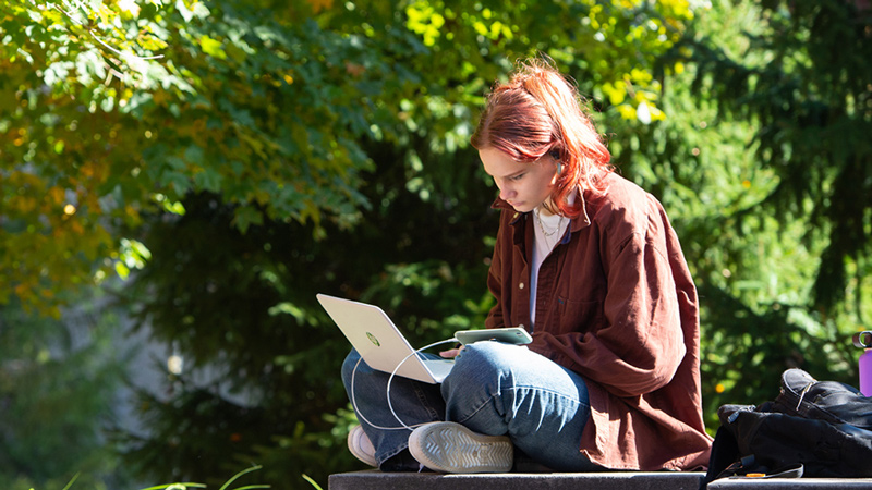A SIUE student working at a picnic table in The Gardens at SIUE.