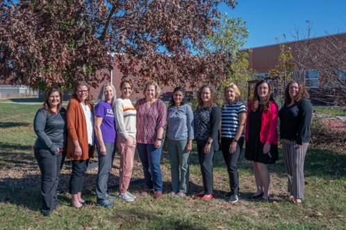 Faculty and staff standing outside in front of a garden