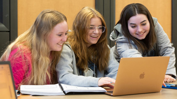 Three SIUE students working around a computer.