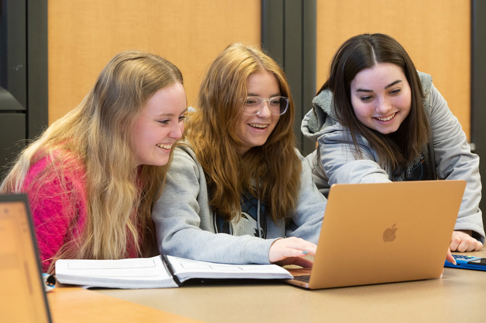 Three SIUE students working around a computer.