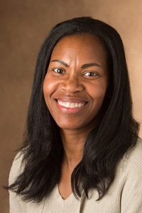 A smiling woman with braided hair wearing a red polo